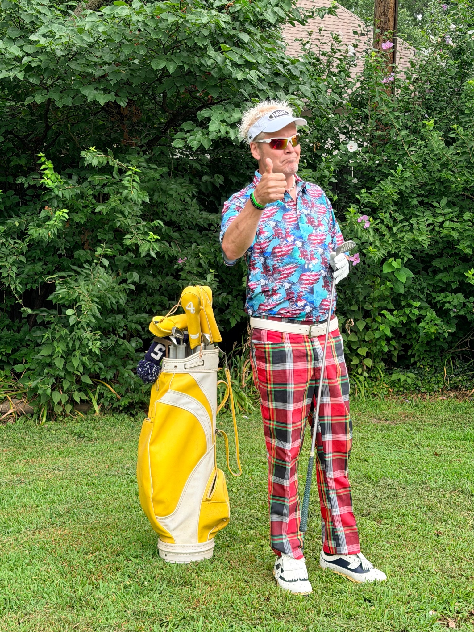 Lonnie The Hawk Hawkins impersonator in plaid golf pants beside a yellow golf bag